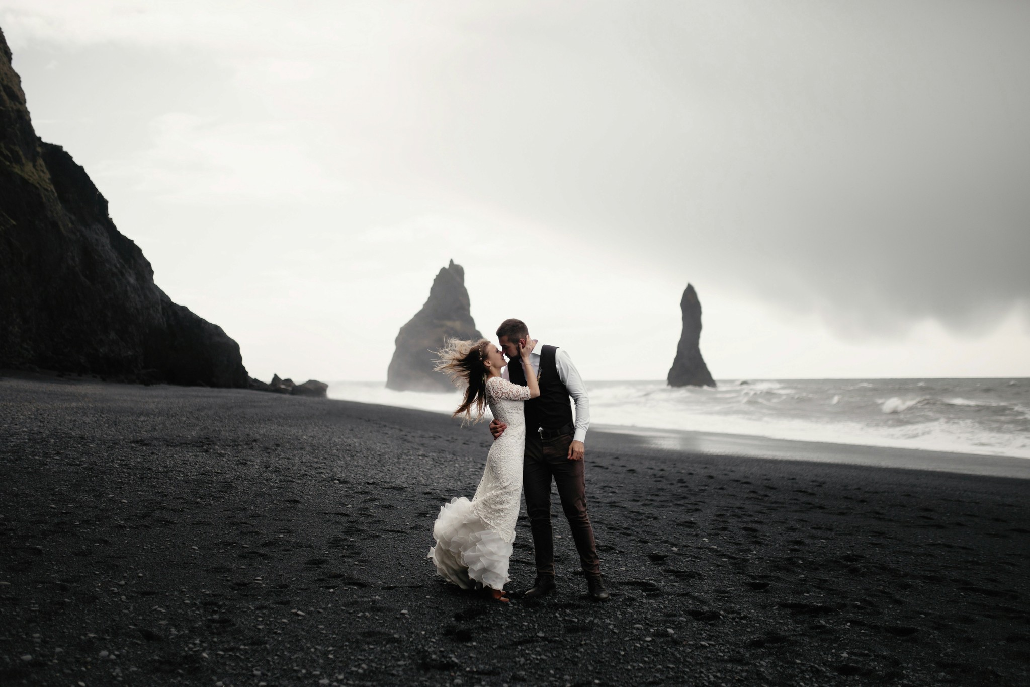 Bride and groom posing on Reynisfjara Black Sand Beach in South Iceland.